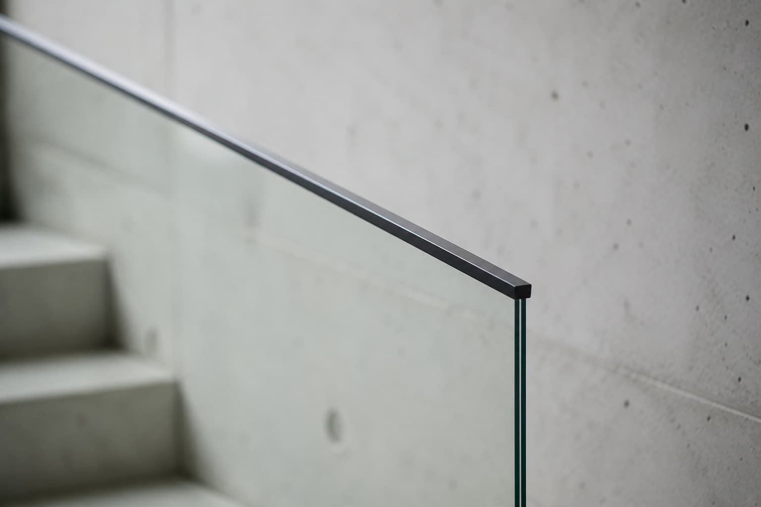 A slim dark rail on frameless glass.
